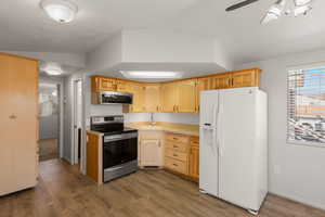 Kitchen featuring light countertops, stainless steel appliances, dark wood-style flooring, ceiling fan, and light wood finish cabinetry