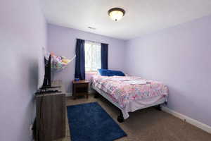Carpeted bedroom featuring baseboards and a textured ceiling