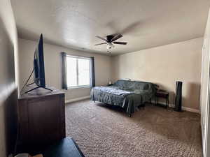 Carpeted bedroom featuring a textured ceiling and ceiling fan
