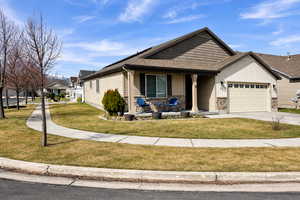 View of front of property with a shingled roof, a porch, an attached garage, driveway, and a front lawn