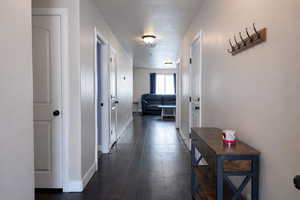 Hall featuring dark wood-type flooring and a textured ceiling
