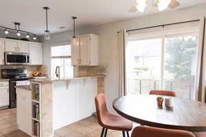 Kitchen with stainless steel appliances, white cabinets, decorative backsplash, and a ceiling fan