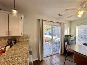 Dining area with a ceiling fan and dark tile patterned flooring