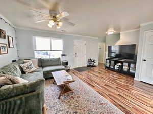 Living room featuring crown molding, a ceiling fan, and wood finished floors