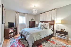 Bedroom featuring light wood-style floors and suspended lighting