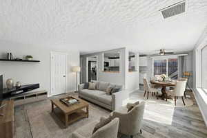 Living area with laminate flooring, ceiling fan and open concept. Virtually staged.