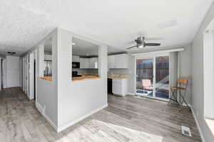 Kitchen featuring butcher block counters, a ceiling fan, light wood-style flooring, black appliances, and white cabinets