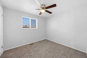 Carpeted spare room with baseboards and ceiling fan