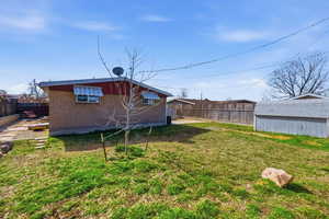 Rear view of house featuring a fenced backyard, brick siding, and a storage unit