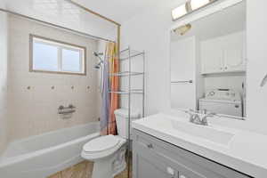 Full bath featuring washer / dryer, vanity, and shower / tub combo