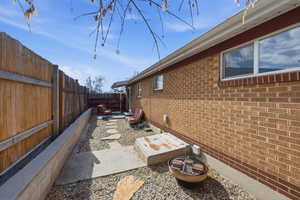 View of side of property featuring a fenced backyard, brick siding, and a patio area