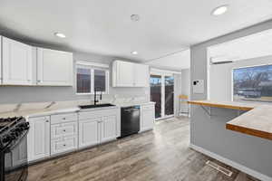 Kitchen featuring butcher block counters, white cabinetry, dishwasher, light wood-style flooring, and healthy amount of natural light