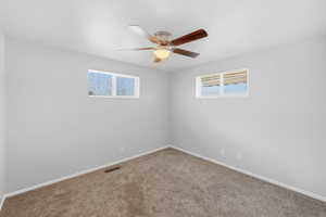 Carpeted spare room featuring baseboards and a ceiling fan