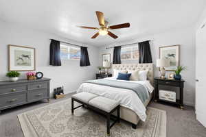 Carpeted bedroom featuring multiple windows and ceiling fan