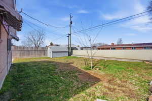 Fenced backyard featuring a shed