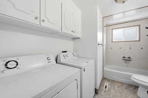 Laundry area with washing machine and dryer and light tile patterned flooring