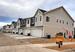View of front facade featuring a residential view, a garage, board and batten siding, and driveway