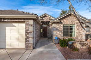 View of front of home with a garage, stone siding, and driveway