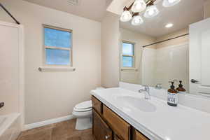 Bathroom featuring vanity, dark tile patterned flooring, shower / washtub combination, and a chandelier