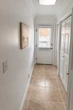 Doorway to outside featuring stone finish flooring and ornamental molding