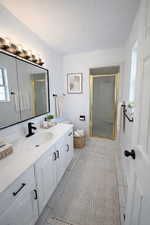 Primary Bathroom with a stall shower, vanity, a textured ceiling, and light tile patterned flooring