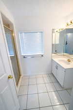 Full bathroom with vanity, a stall shower, light tile patterned flooring, and a textured ceiling