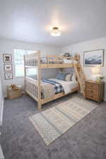 Bedroom with dark colored carpet and a textured ceiling