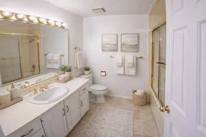 Bathroom featuring combined bath / shower with glass door, vanity, and light tile patterned floors. AI decor.