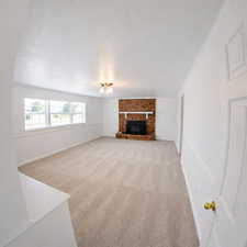 Unfurnished living room featuring light carpet, a textured ceiling, and a fireplace