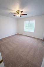 Carpeted spare room with a textured ceiling and a ceiling fan