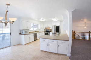 Kitchen featuring a peninsula, stainless steel appliances, white cabinets, and a chandelier