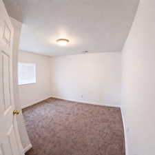 Unfurnished room featuring dark colored carpet and a textured ceiling