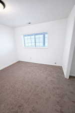 Spare room with dark carpet and a textured ceiling