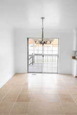 Unfurnished dining area featuring a chandelier, light tile patterned floors, a textured ceiling, and crown molding
