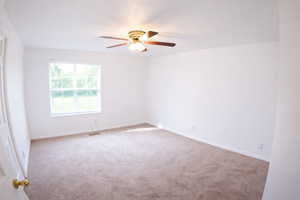 Carpeted empty room with baseboards and a ceiling fan