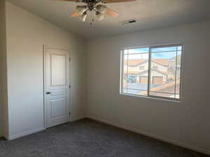 Empty room with ceiling fan and dark colored carpet