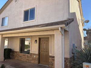 View of exterior entry featuring stone siding, stucco siding, and a porch