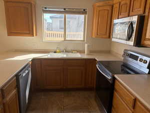 Kitchen featuring stainless steel appliances, wood finish cabinets, and light countertops