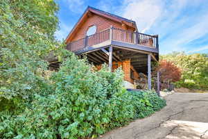 View of side of home featuring faux log siding and a wooden deck