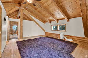 Bonus room featuring wooden ceiling, vaulted ceiling with beams, rustic walls, light wood-type flooring, and healthy amount of natural light