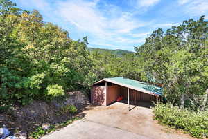 View of outdoor structure with driveway and a wooded view