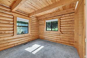 Spare room with carpet floors, a wood ceiling with exposed beams, and log walls