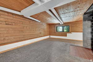 Spare room with rustic walls, wooden ceiling, and carpet floors
