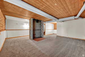 Finished basement featuring wood ceiling and light carpet