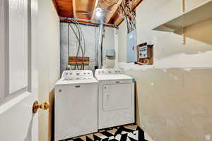 Laundry area with light flooring, washing machine and clothes dryer, and electric panel