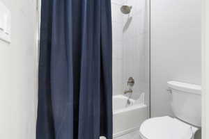 Full bath featuring toilet and shower / bath combination with curtain