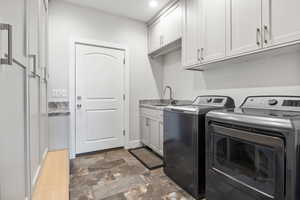 Laundry room featuring cabinet space, separate washer and dryer, stone finish flooring, and recessed lighting