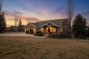 Craftsman house featuring stone siding, a yard, an attached garage, and driveway