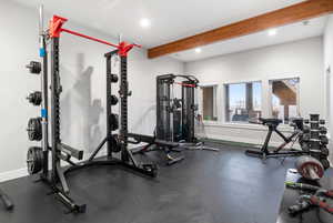 Gym featuring dark flooring, beam ceiling, and recessed lighting
