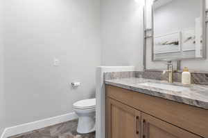 Half bathroom with vanity and dark stone finish flooring